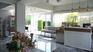 A spacious living area with a large window, a ceiling fan, and a dining area with a table and chairs. - Nan Nakara Boutique (Nan)