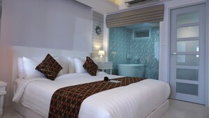 A hotel room with a large bed, a bathroom with a bathtub, and a sliding glass door. - Nan Nakara Boutique (Nan)