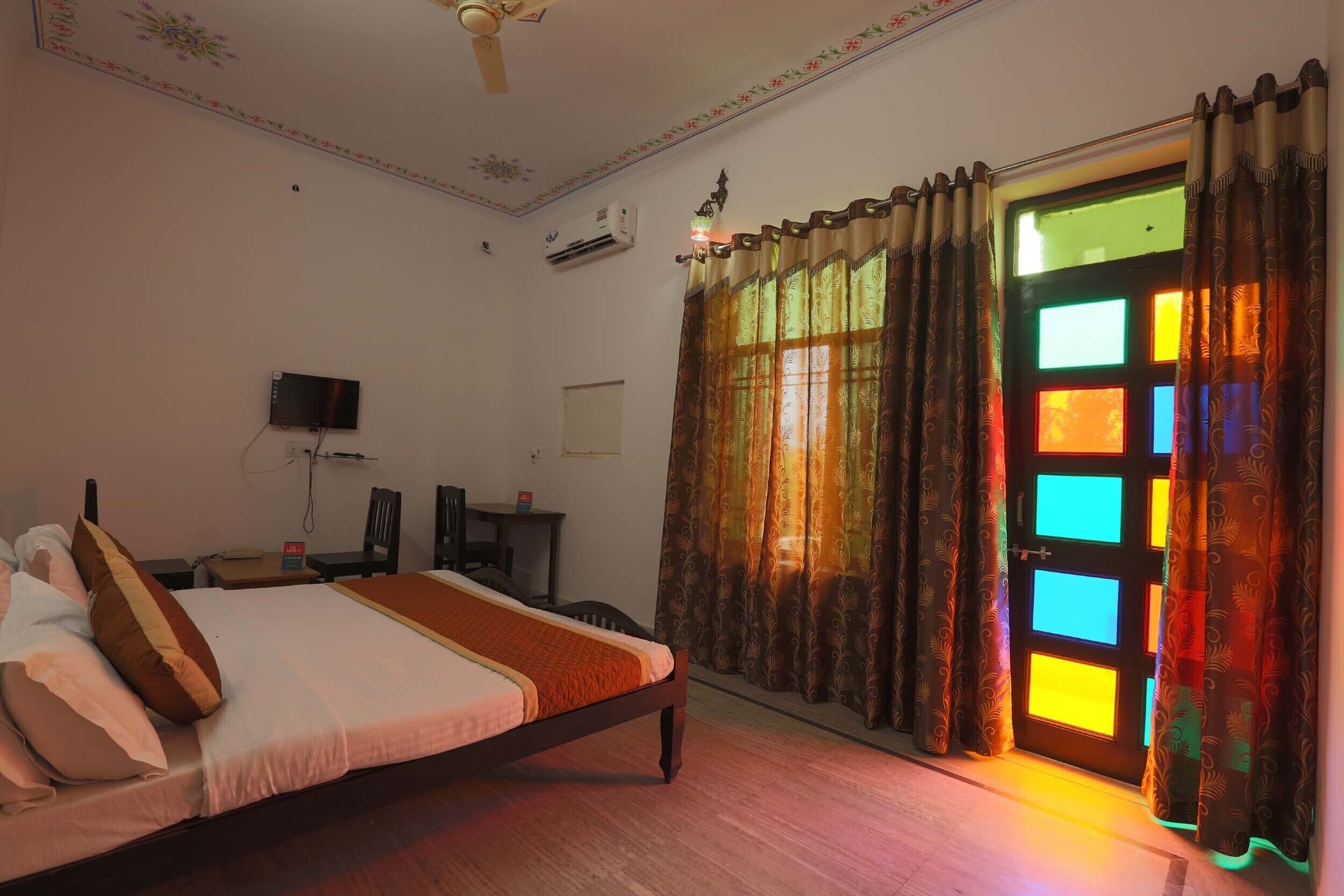 A bedroom with a bed, a desk, a chair, and a television.