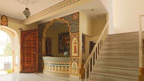 A grand entrance with a wooden door, intricate wall decorations, and a marble staircase. - Hotel Green Haveli (Pushkar)