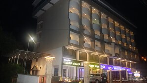 Un hotel de varios pisos con balcones, una entrada cubierta y señalización para un restaurante y un banco.