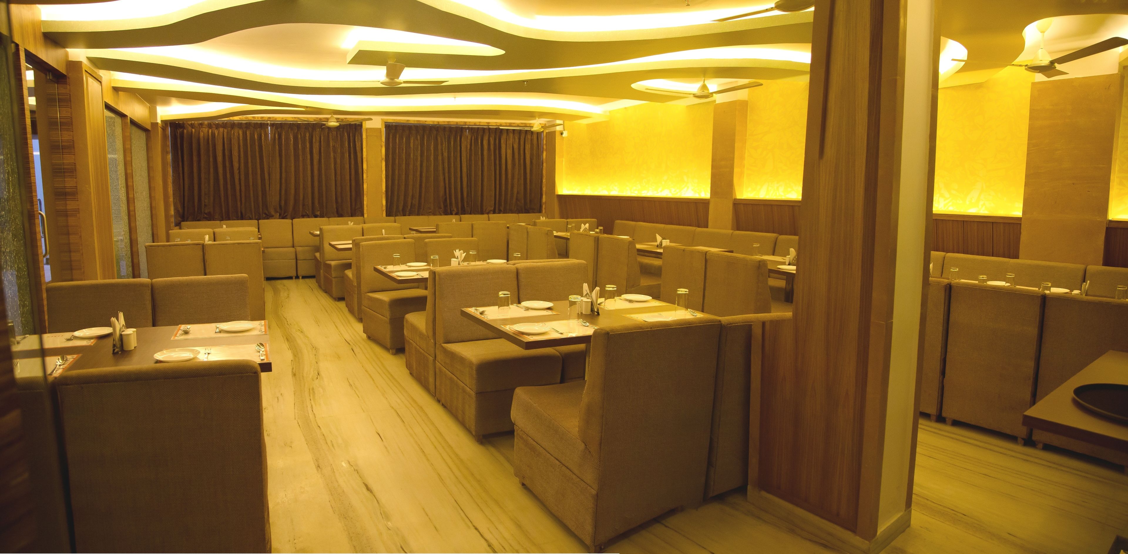 A restaurant with booths and tables, wooden flooring, and modern lighting fixtures.