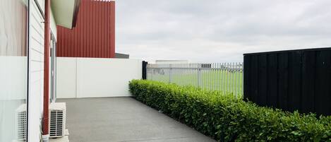 A narrow concrete pathway leading to a building with a red roof and white walls.