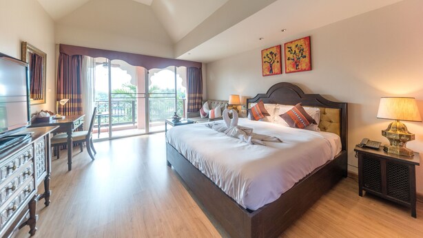 A spacious bedroom with a large bed, a desk, and a television. - Sheik Istana Hotel Chiangmai  (Chiang Mai)