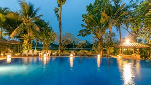 A swimming pool with lounge chairs and umbrellas, surrounded by palm trees and a gazebo. - Sheik Istana Hotel Chiangmai  (Chiang Mai)