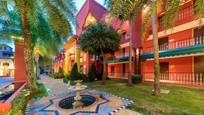 A courtyard with a fountain, palm trees, and a building with balconies. - Sheik Istana Hotel Chiangmai  (Chiang Mai)