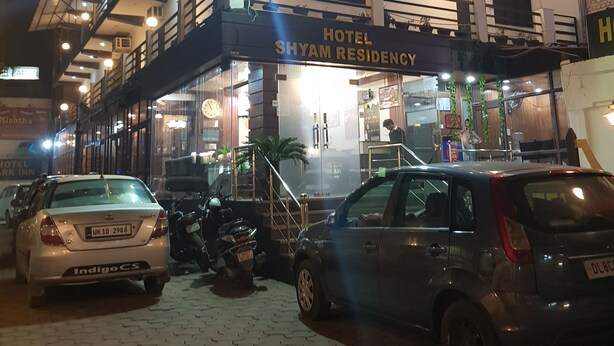 Een hotel met meerdere verdiepingen, balkons en een bord met de tekst 'HOTEL SHYAM RESIDENCY'.