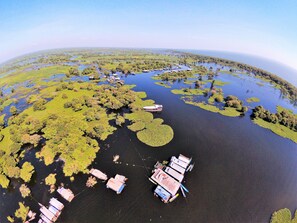 Luchtbeeld van een rivierengebied met verschillende boten afgemeerd langs de oevers, omgeven door weelderige begroeiing en waterlichamen.