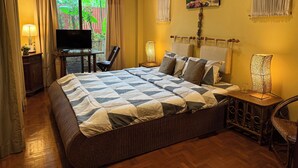 Quarto com cama grande, televisão, escrivaninha e cadeira.