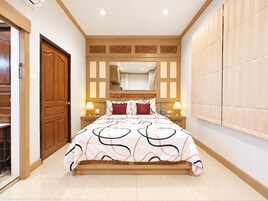 Habitación de hotel con una cama grande, cabecera de madera, mesitas de noche con lámparas y un armario.