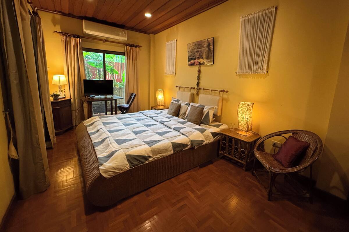 A bedroom with a large bed, a television, a desk, and a chair.
