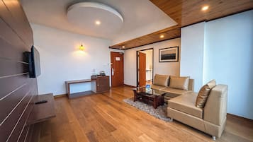 Una sala de estar moderna con piso de madera, un sofá, una mesa de centro y un televisor montado en la pared.