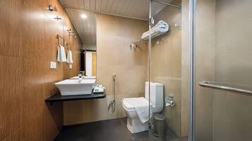 Un baño moderno con tocador de madera, lavamanos, inodoro y cabina de ducha de vidrio.
