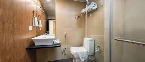 A modern bathroom with a wooden vanity, a sink, a toilet, and a glass shower enclosure.