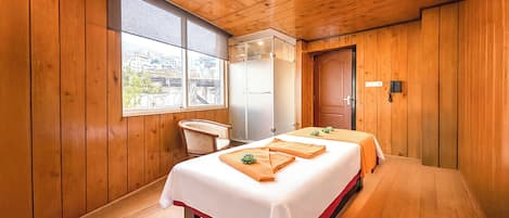 A wooden room with two beds, a window, a door, and a phone on the wall.