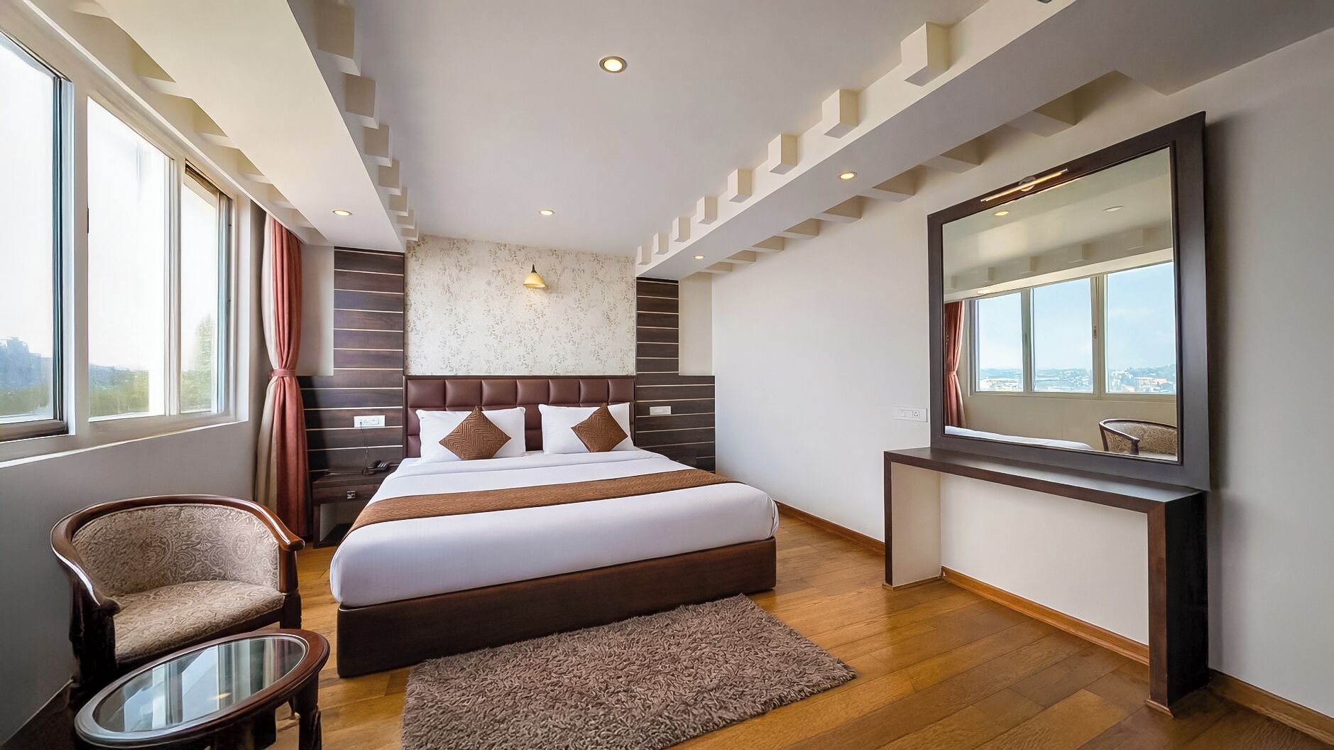 Una habitación de hotel moderna con una cama grande, un escritorio, una silla y un ventanal con vistas a la ciudad.