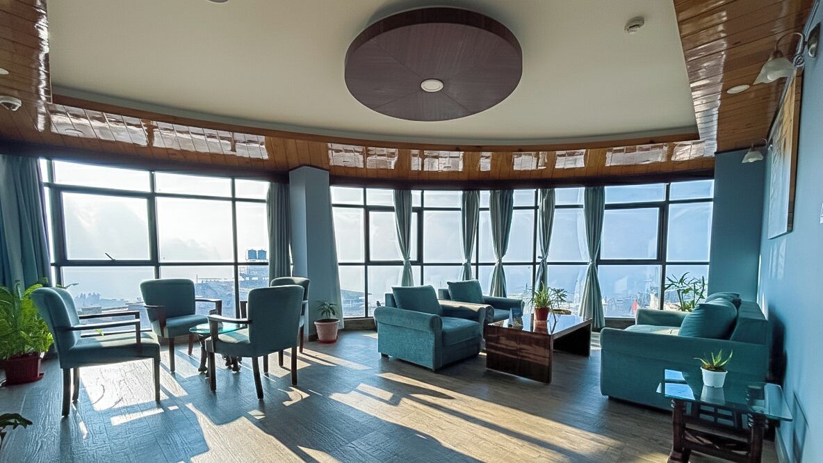 Een ruime lounge met een hoge plafond, grote ramen met uitzicht op de stad, en comfortabele zithoeken.
