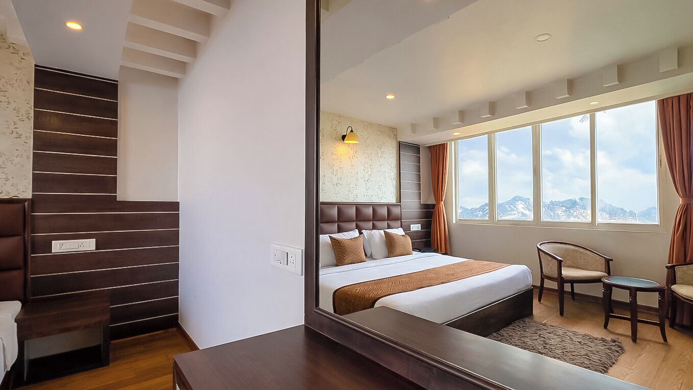 Ein modernes Hotelzimmer mit einem großen Bett, einer Sitzecke mit Stuhl und Tisch, einer Treppe und einem großen Fenster mit Blick auf die Stadt.