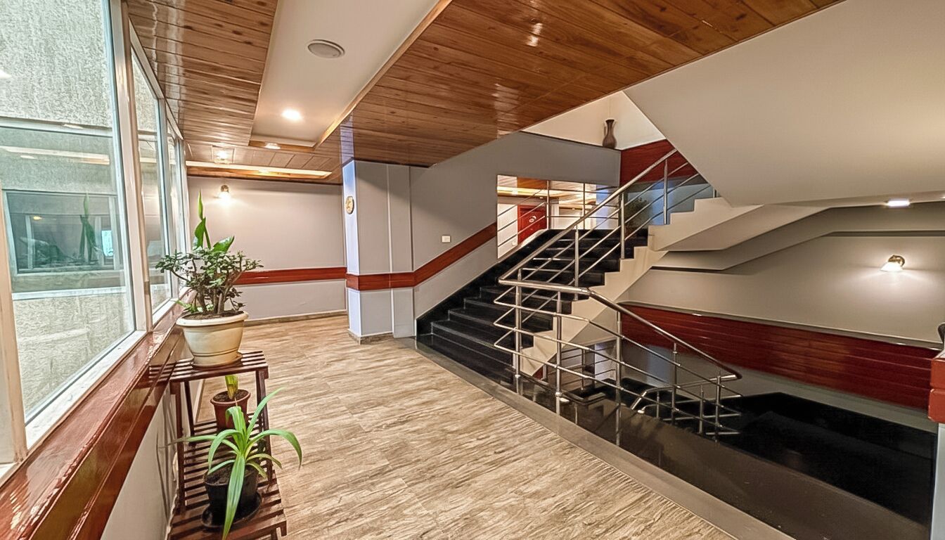 Ein modernes Interieur mit Holzboden, einer Treppe mit Glastrennstäben und einem Blumentopf auf einem Holzgestell.