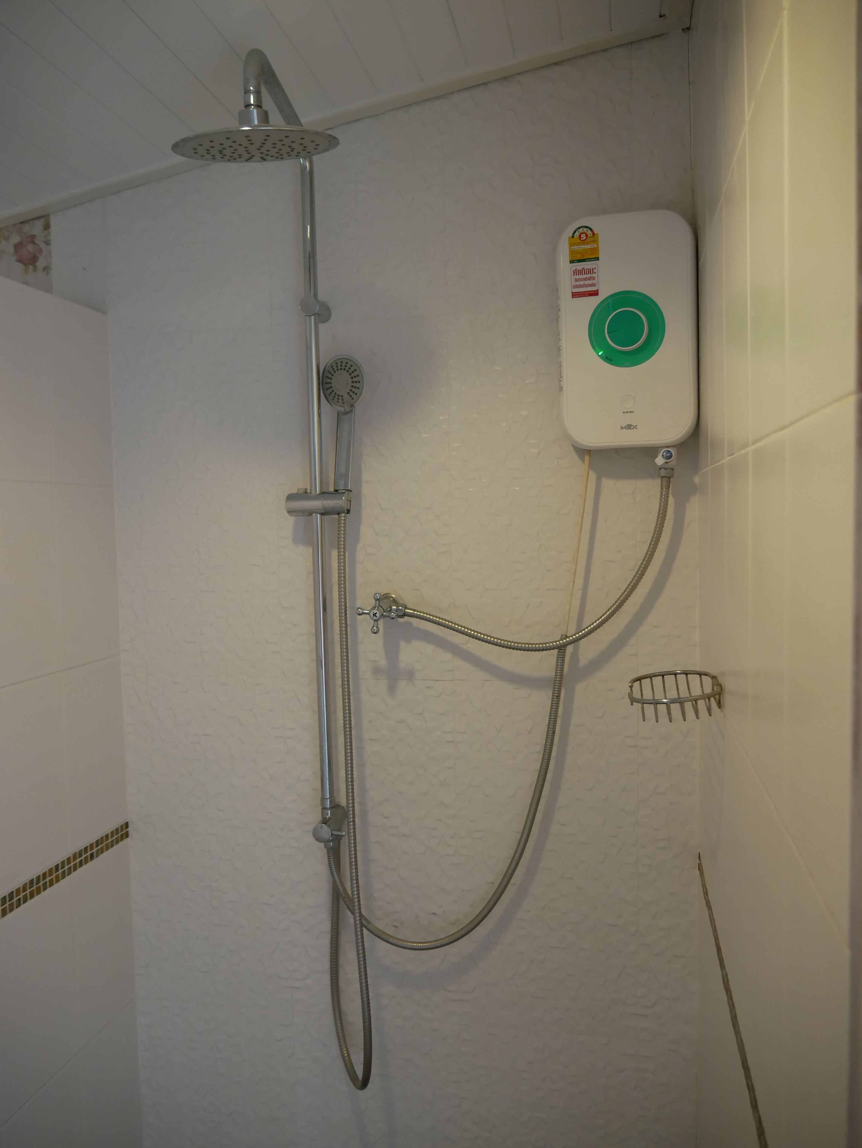 A shower with a handheld showerhead, a wall-mounted control panel, and a handheld hose.