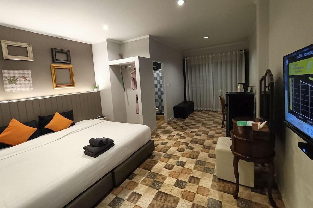 Een hotelkamer met een bed, bureau, stoel, televisie en kledingkast.