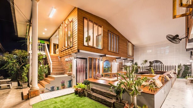 Ein modernes Haus mit Holzfassade, einem gepflegten Rasen und verschiedenen Kübelpflanzen.
