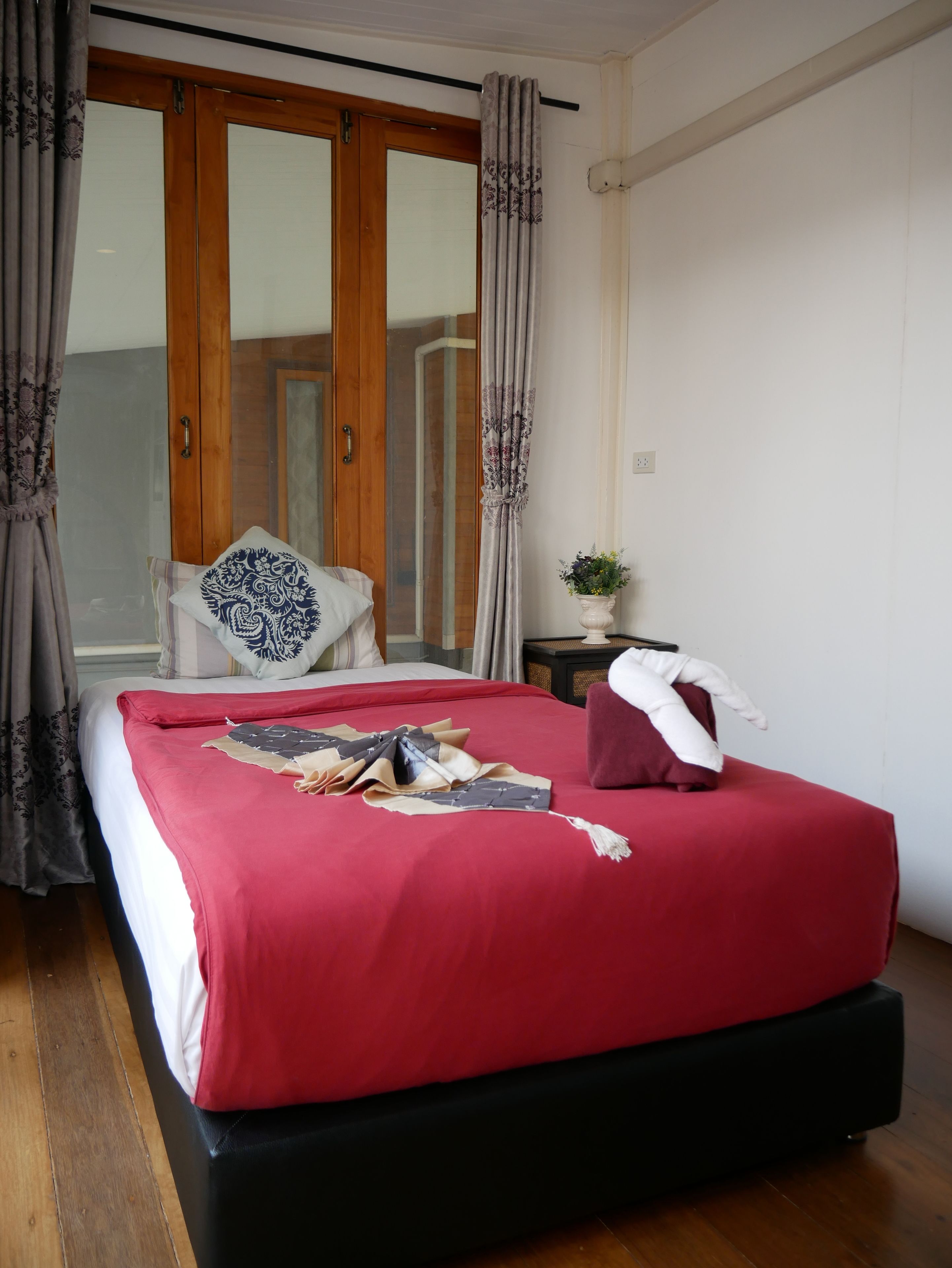 A hotel room with a large bed, wooden wardrobe, and a window with curtains.