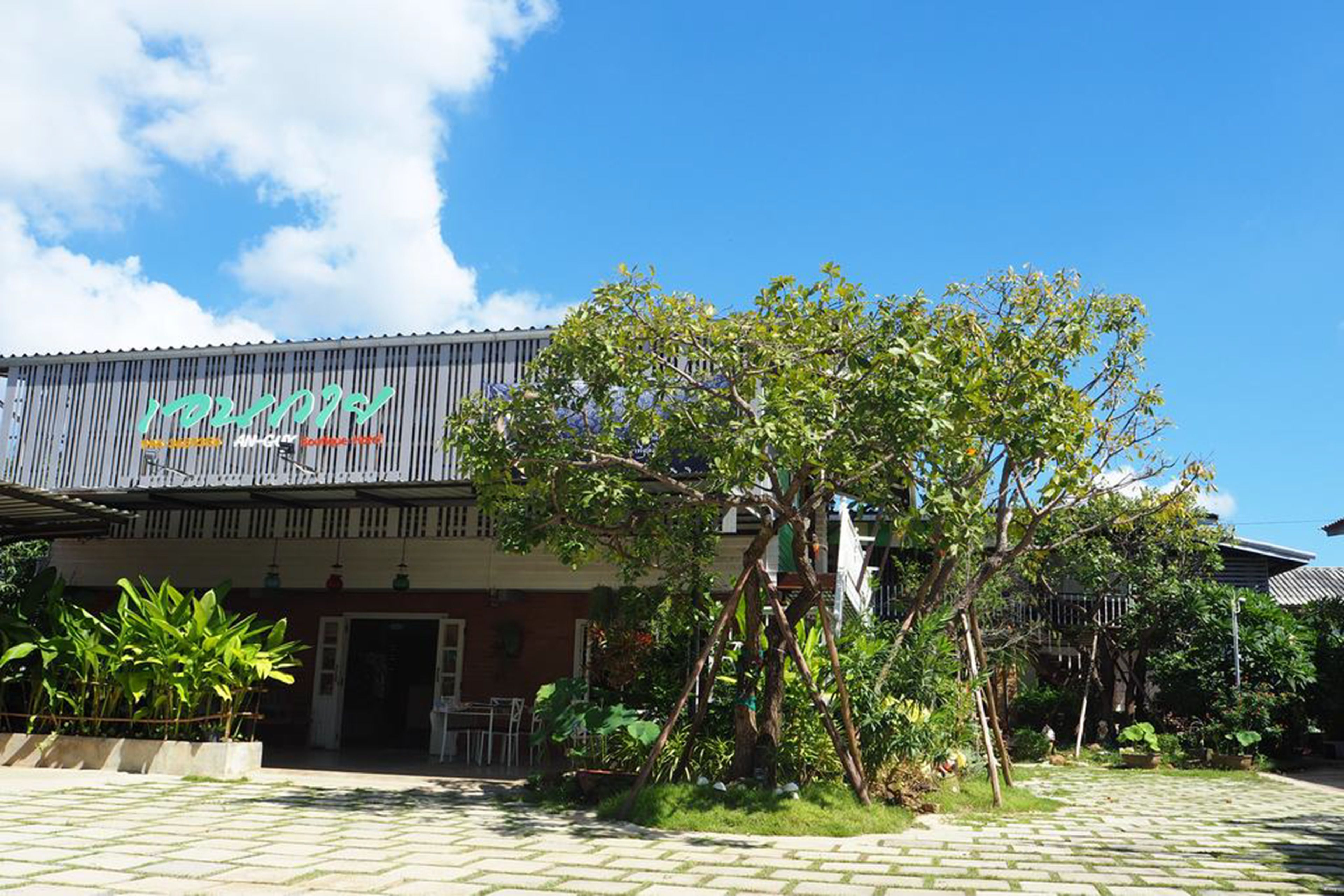 A building with a sign that reads "HOTEL" and a tree in front.