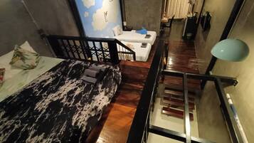 Una sala moderna con un sofá estampado en mármol, una escalera y vistas de la ciudad.