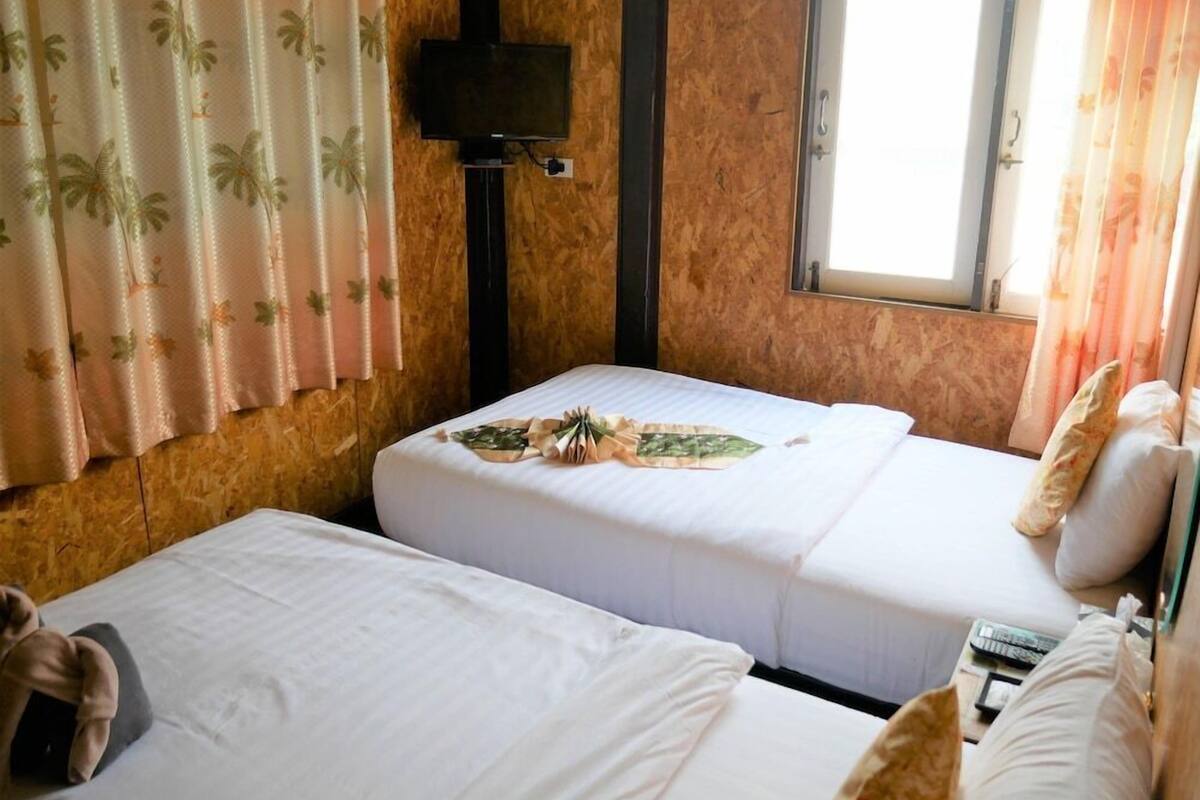 Una habitación con dos camas, televisión y ventana con cortinas.