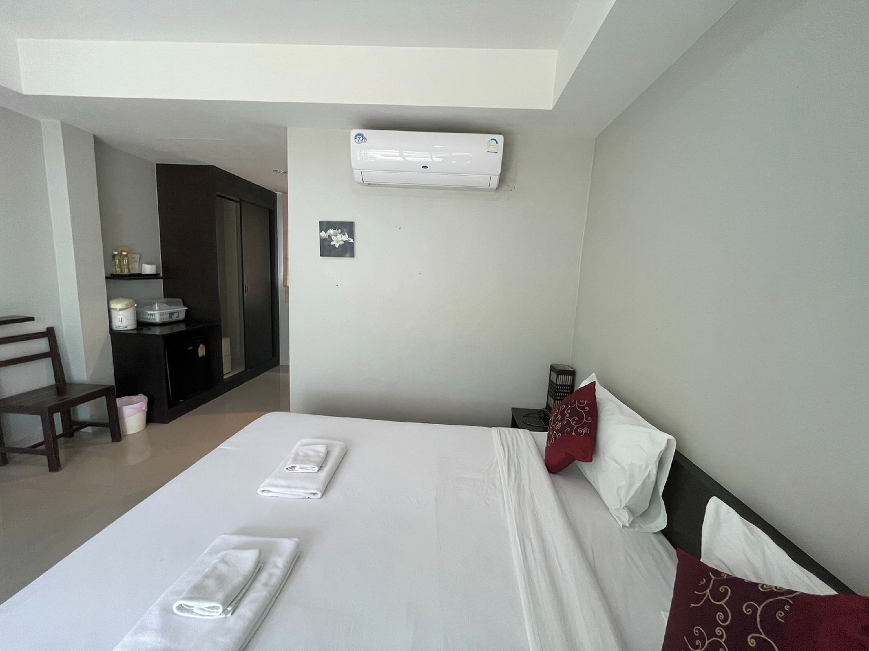 Hotelkamer met een bed, een bureau, een stoel, een klein tafeltje en een wandairconditioner.