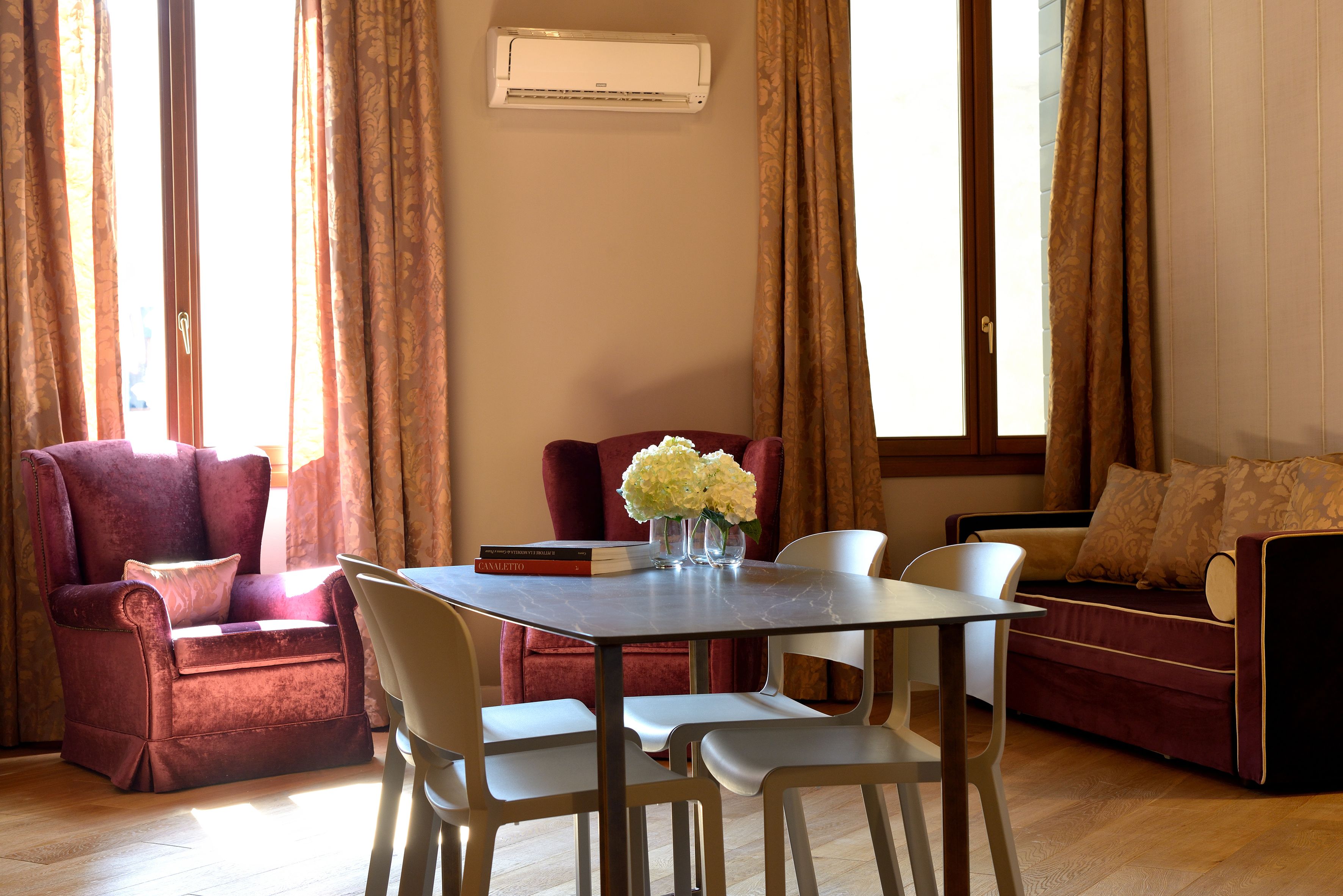 Un salon comprenant une table à manger, deux fauteuils, un canapé et une fenêtre avec des rideaux.