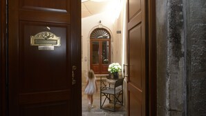 A wooden door with a brass plaque, a stone wall, and a small table with a potted plant. - Residence La Fenice (Venice)