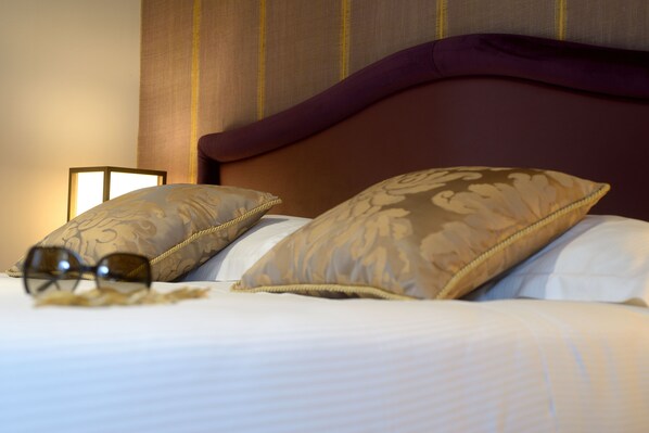 A neatly made bed with patterned pillows and a pair of glasses on the bed. - Residence La Fenice (Venice)