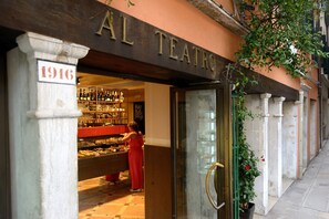 El exterior de AL TEATRO, con una tienda de vinos visible en el interior.