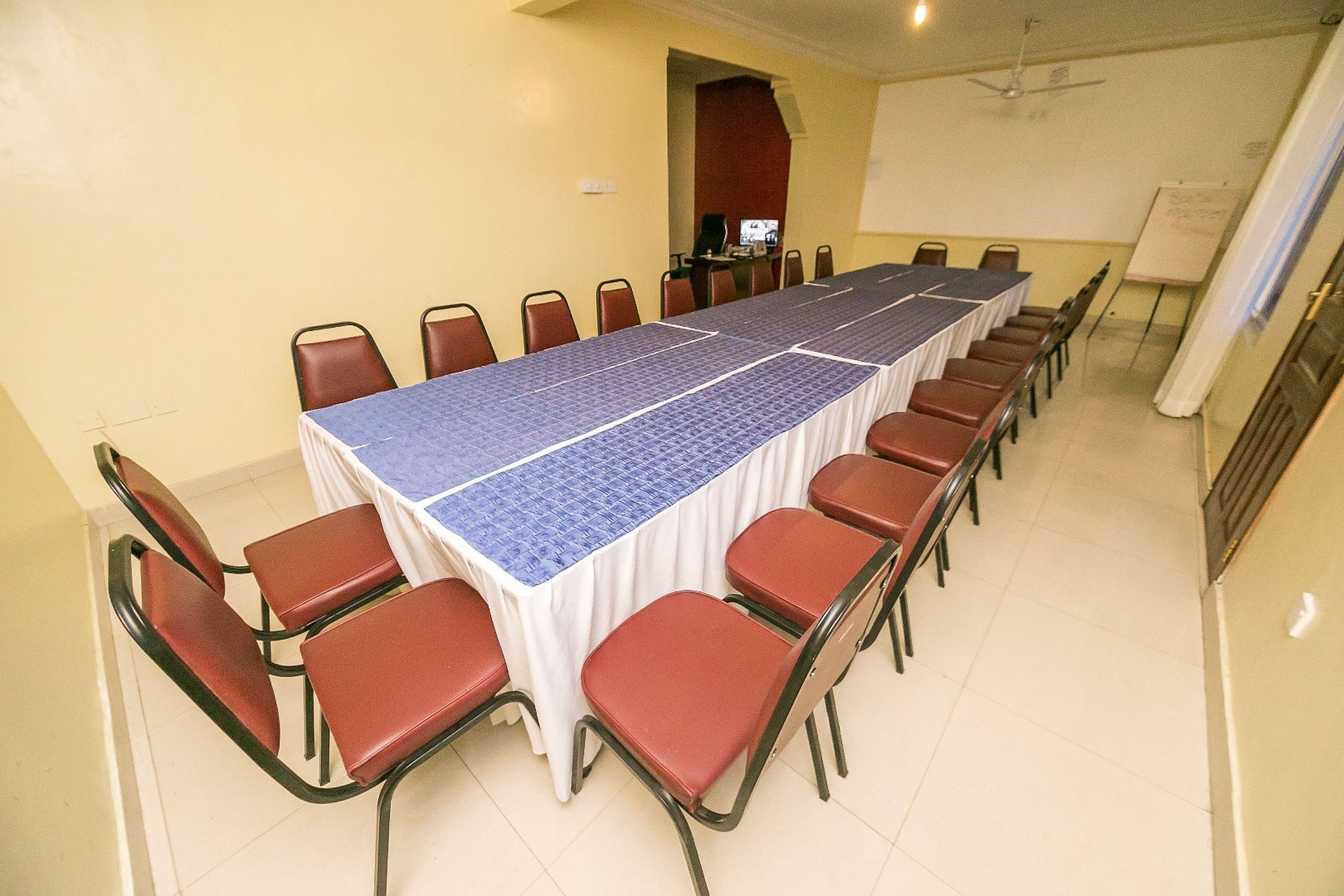 A conference room with a long table and red chairs.