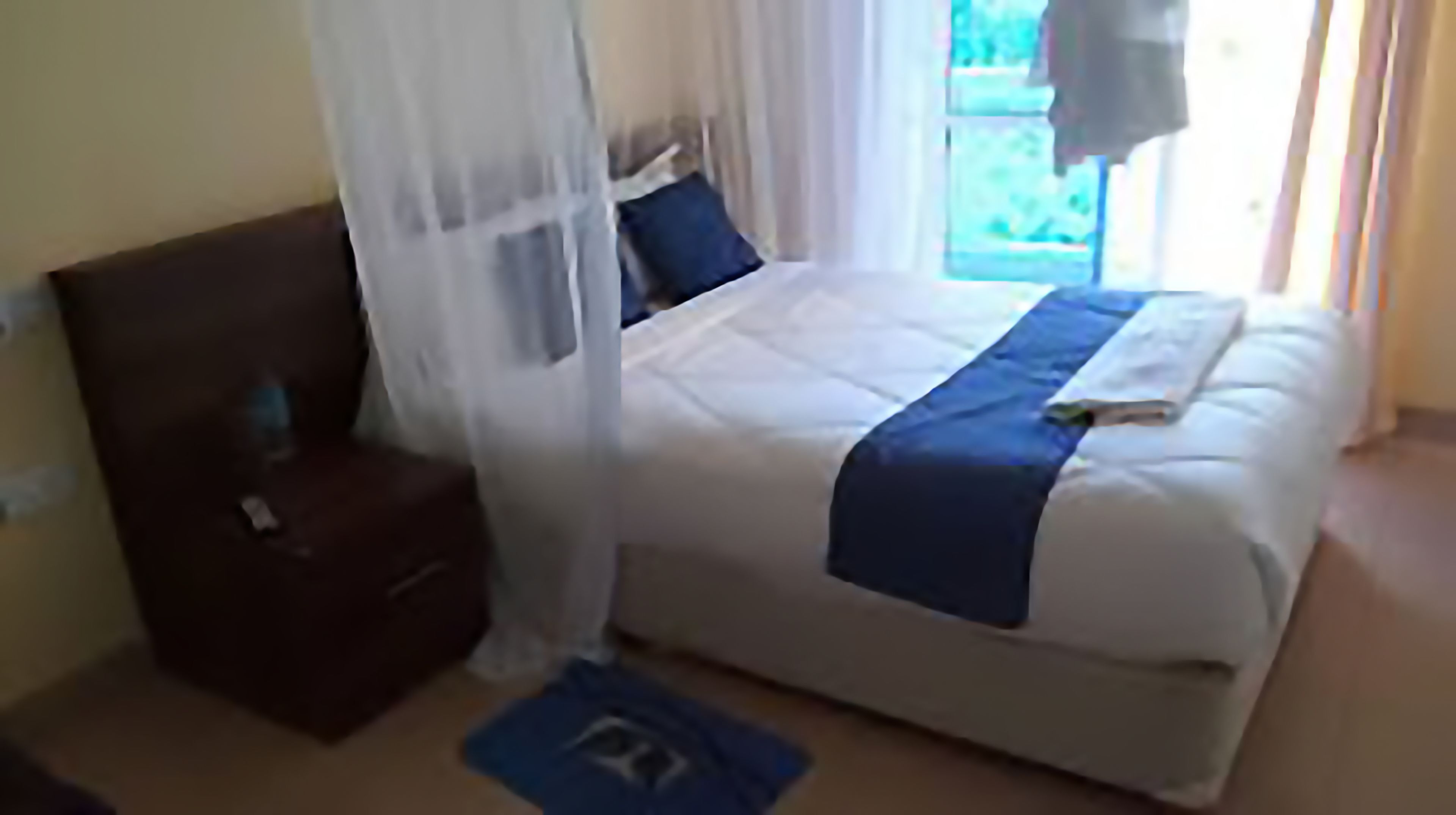 Un dormitorio con cama, mesita de noche y ventana con cortinas.