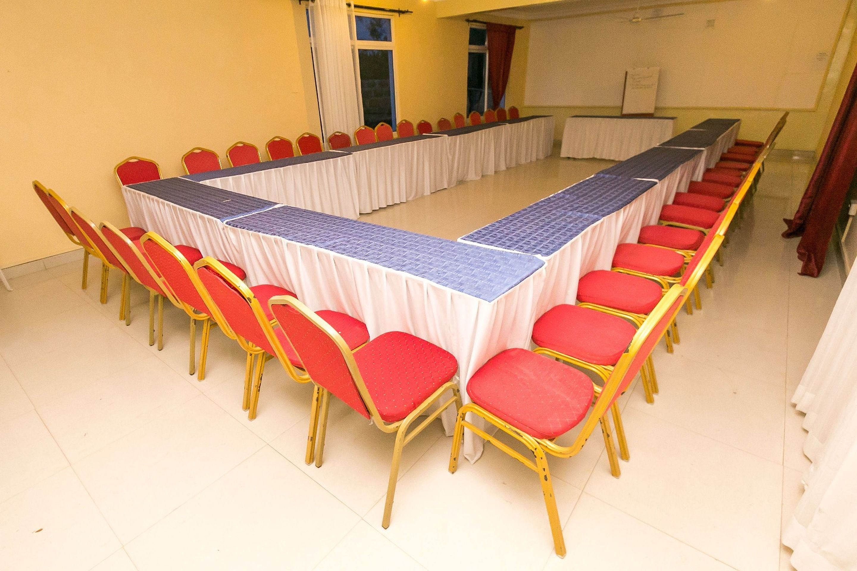 Un salón de conferencias con una larga mesa y sillas rojas.