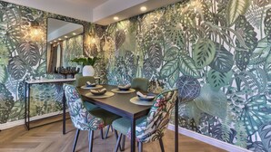 A dining area with a table set for four, surrounded by chairs with floral upholstery. - 437 St Martini Gardens (Cape Town)