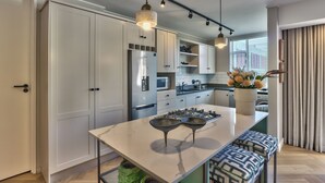 A modern kitchen with white cabinets, stainless steel appliances, and pendant lighting. - 437 St Martini Gardens (Cape Town)