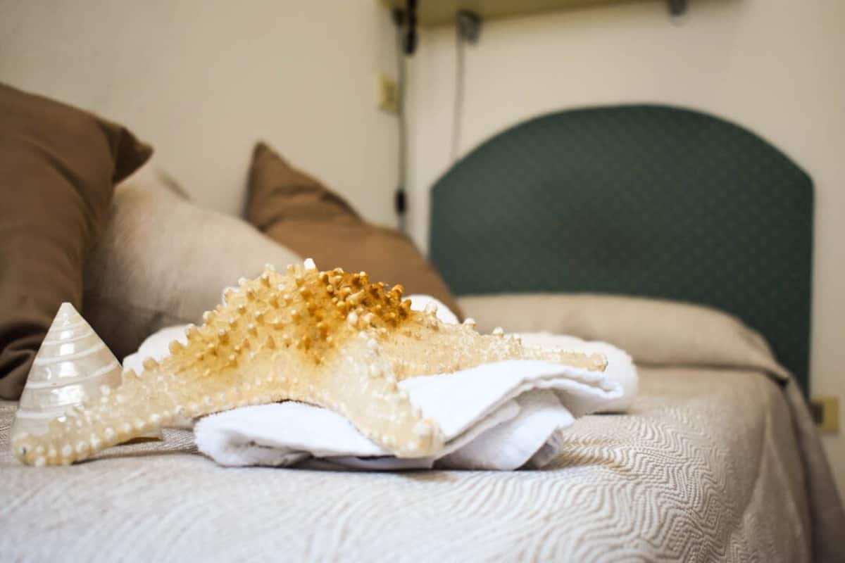 A bed with a textured white bedspread, a white pillow, and a decorative item resembling a seashell with golden spikes.