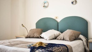 A bed with a teal headboard, beige bedding, and a starfish decoration. - Hotel Embassy Pesaro (Pesaro)