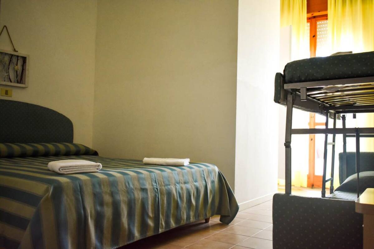 A hotel room with a single bed, a bunk bed, and a chair.