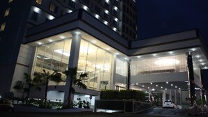 Ein modernes Hotel mit Glasfassade, mehreren Etagen und einem gut beleuchteten Eingang.