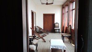 Una habitación amplia con piso de madera, un ventilador de techo y un ventanal grande.
