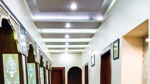 Un pasillo con puertas decoradas, piso de baldosas y una escalera al final.