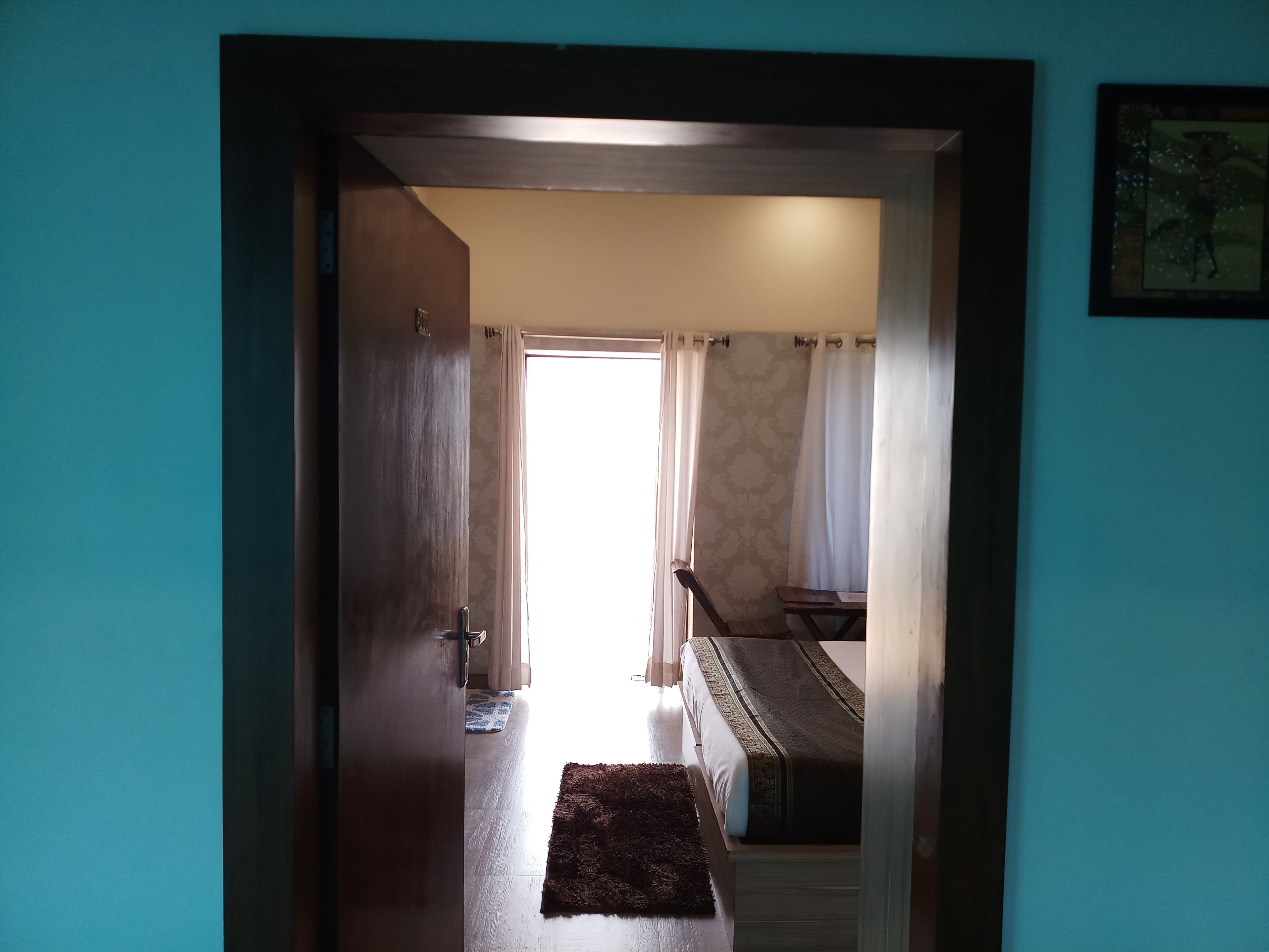 A hallway leading to a bedroom with a bed, a small table, and a piano.