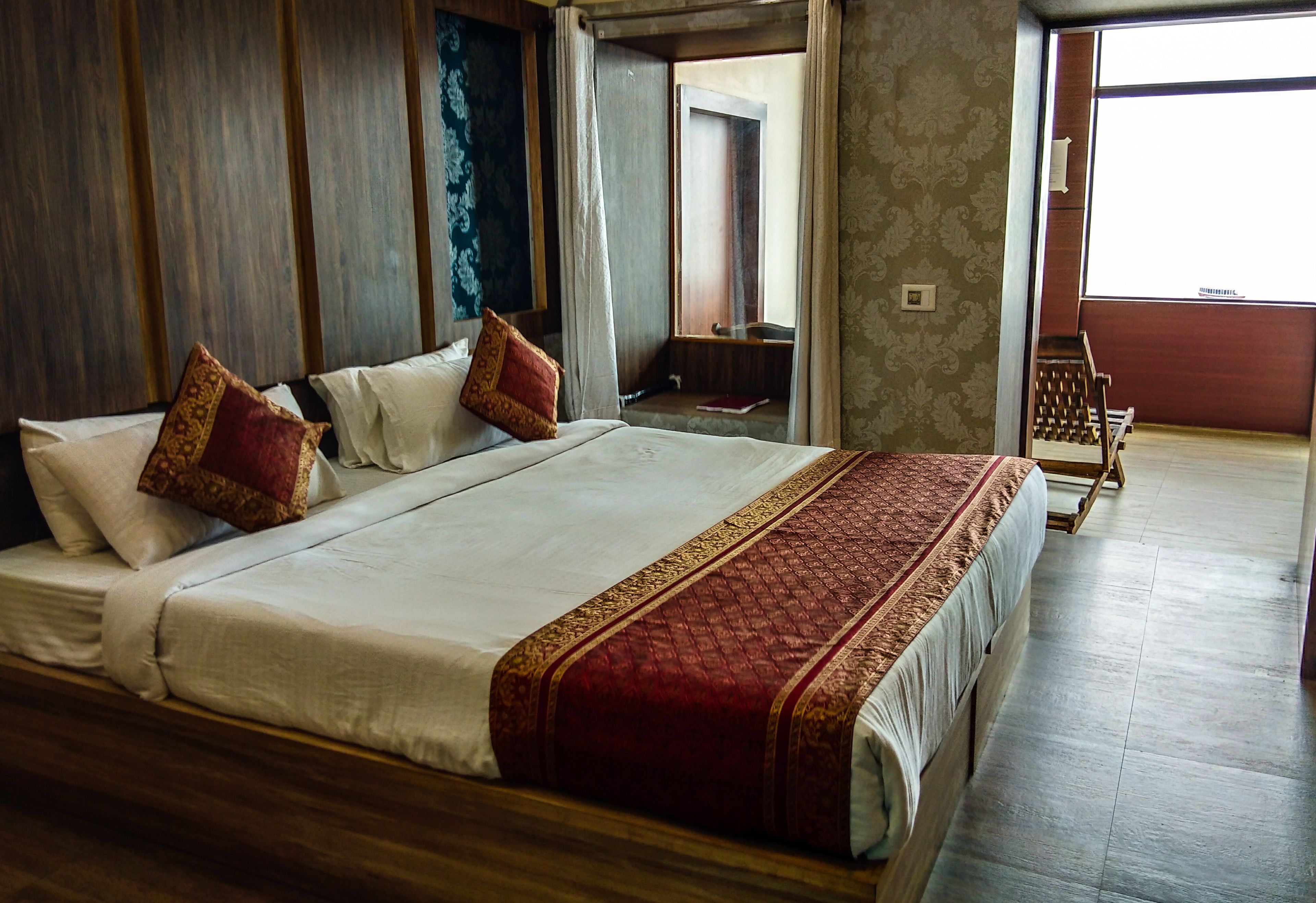 A large bed with a red and white bedspread, wooden headboard, and two pillows.
