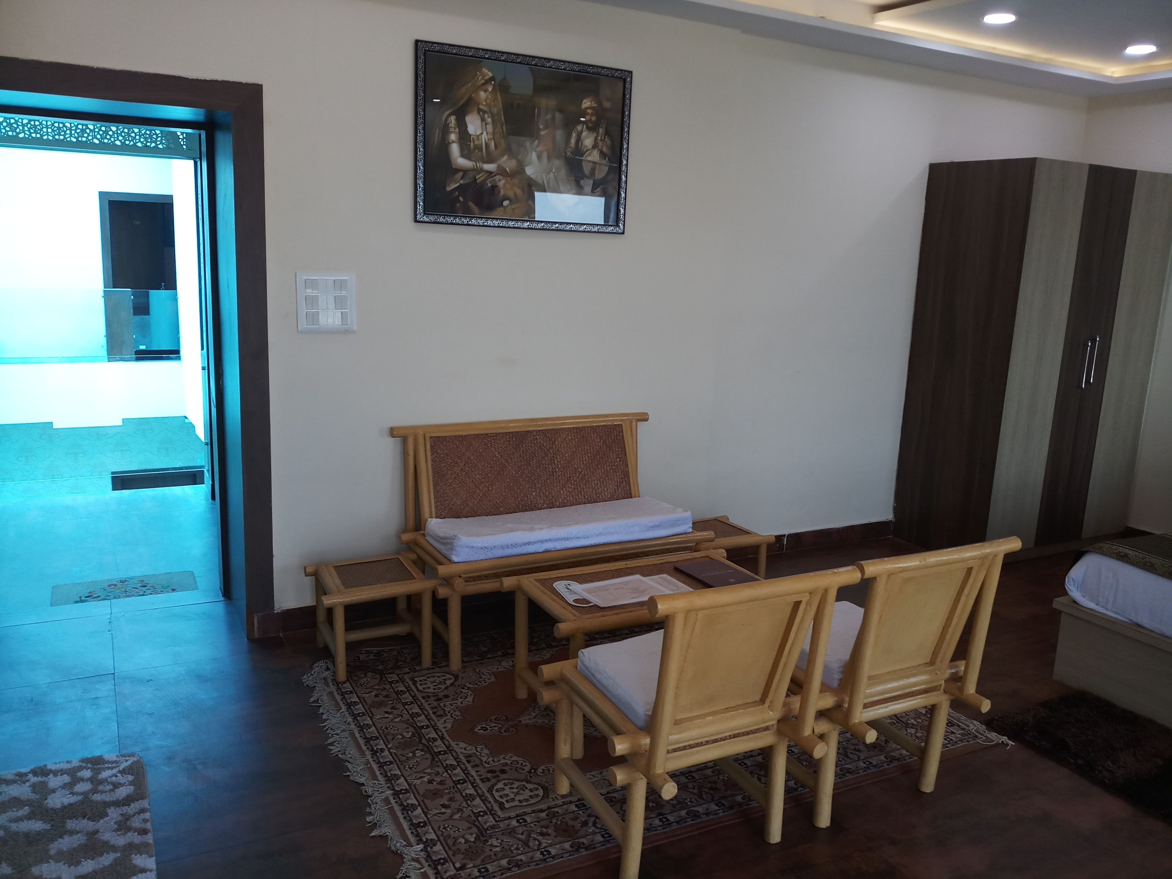 Una habitación con cama, escritorio, dos sillas, armario y un cuadro en la pared.