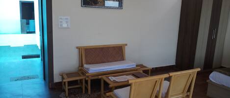 A room with a bed, a desk, two chairs, a wardrobe, and a framed picture on the wall.